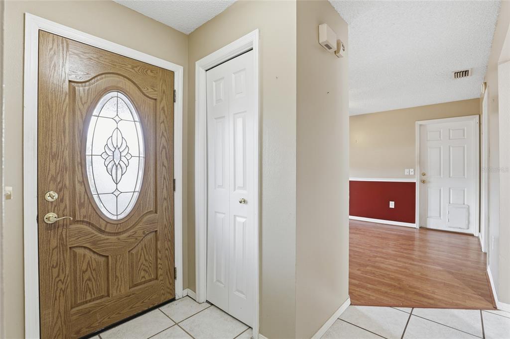 An entryway features a wood-paneled front door, a white closet door, and tile flooring — 3940 SW 134TH STREET, OCALA, FL