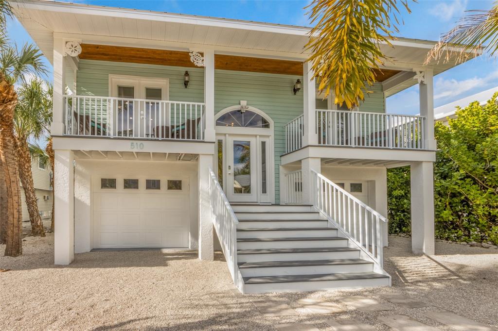 A light green two-story house with a white garage and palm trees in the front yard — 510 MAGNOLIA AVENUE, ANNA MARIA, FL