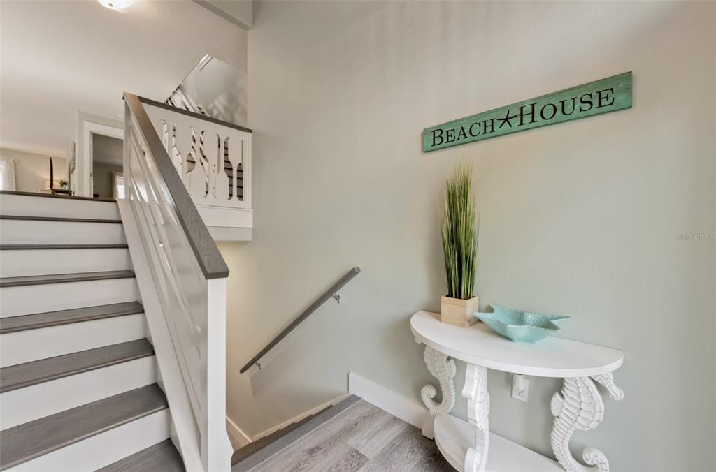 A two-story elevated house with light green siding, a white garage, and a front staircase — 510 MAGNOLIA AVENUE, ANNA MARIA, FL