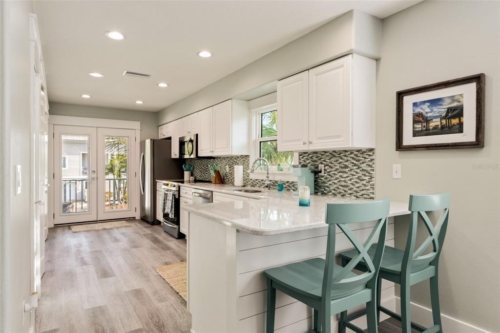 A staircase with gray treads and white railings stands beside a console table with decor — 510 MAGNOLIA AVENUE, ANNA MARIA, FL