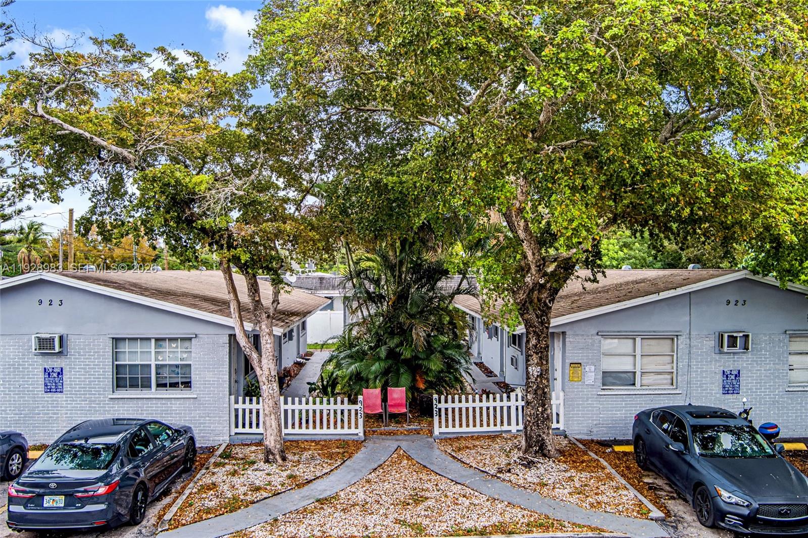 An exterior view of a grey, single-story apartment building with two parked cars — 923 SE 2nd Ave # 6, Hallandale Beach FL 33009, HALLANDALE BEACH, FL