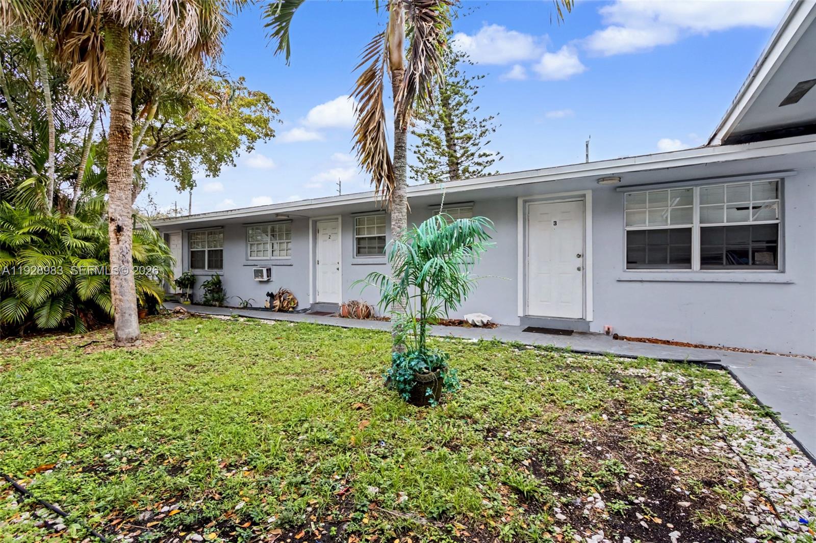 A single-story gray apartment building with multiple unit doors and a grassy front yard — 923 SE 2nd Ave # 6, Hallandale Beach FL 33009, HALLANDALE BEACH, FL