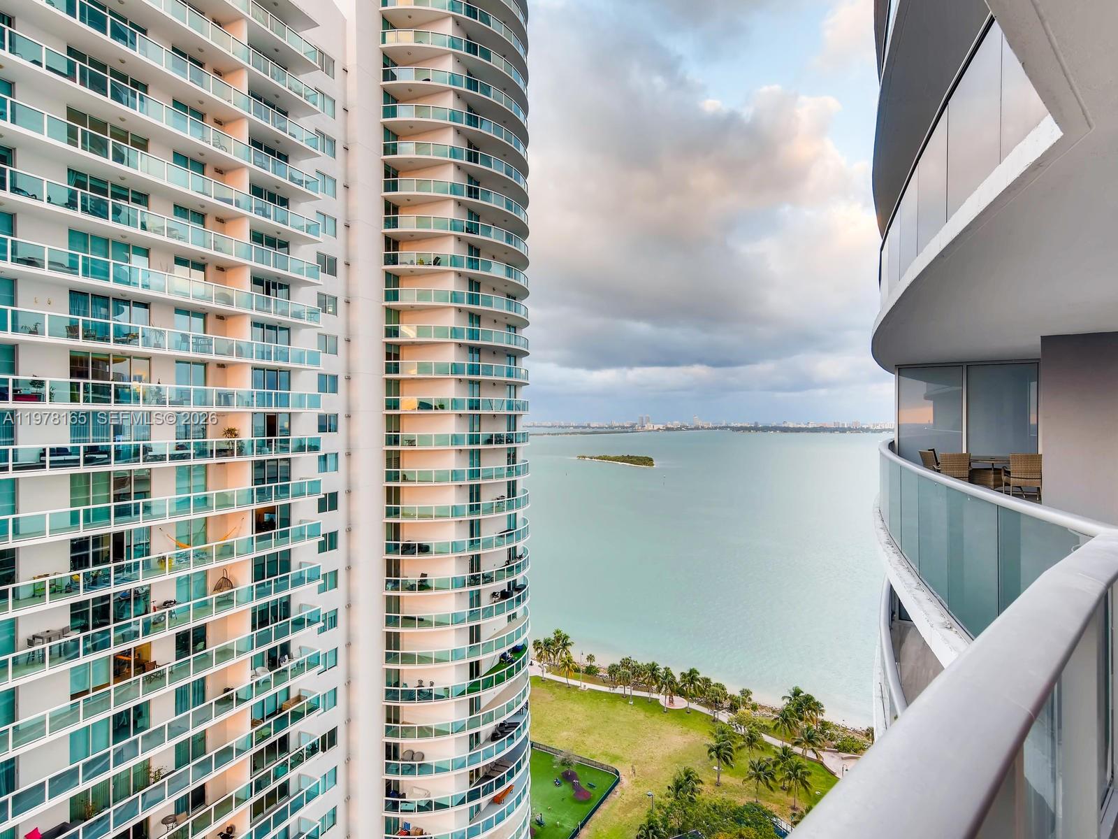 A view from a balcony overlooking a bay, a park, and a neighboring high-rise building — 488 NE 18th St # 2507, Miami FL 33132, MIAMI, FL