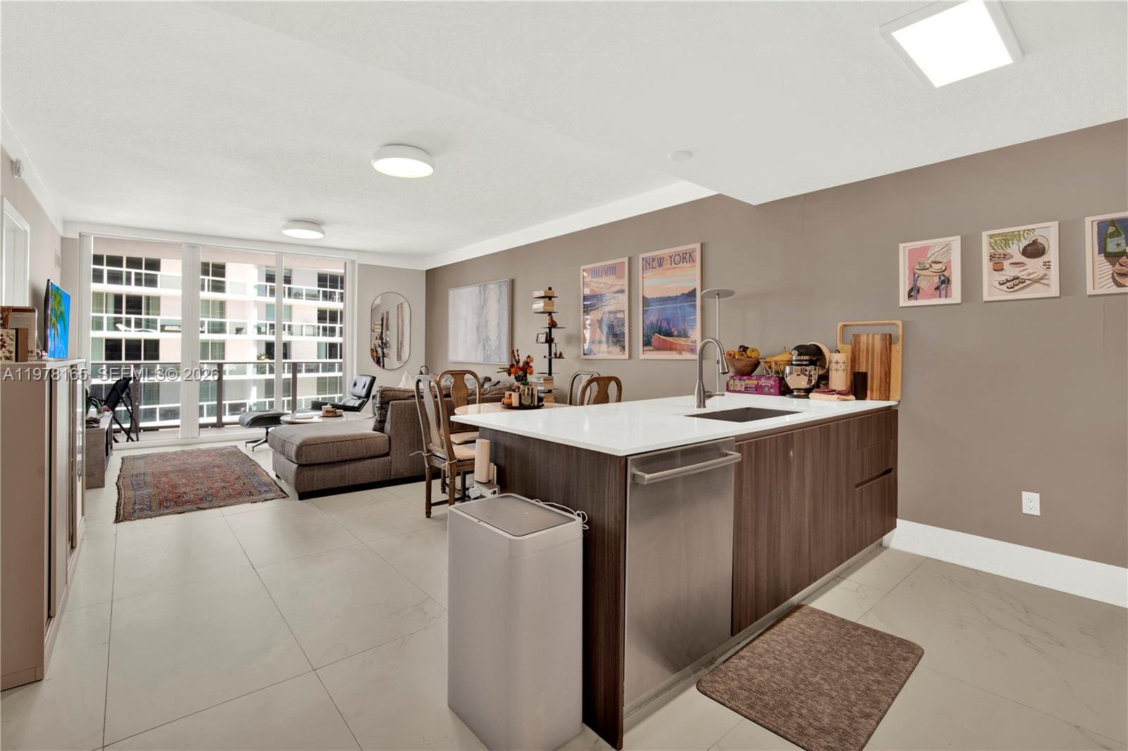 A modern open-concept kitchen and living area with a central island and balcony access — 488 NE 18th St # 2507, Miami FL 33132, MIAMI, FL