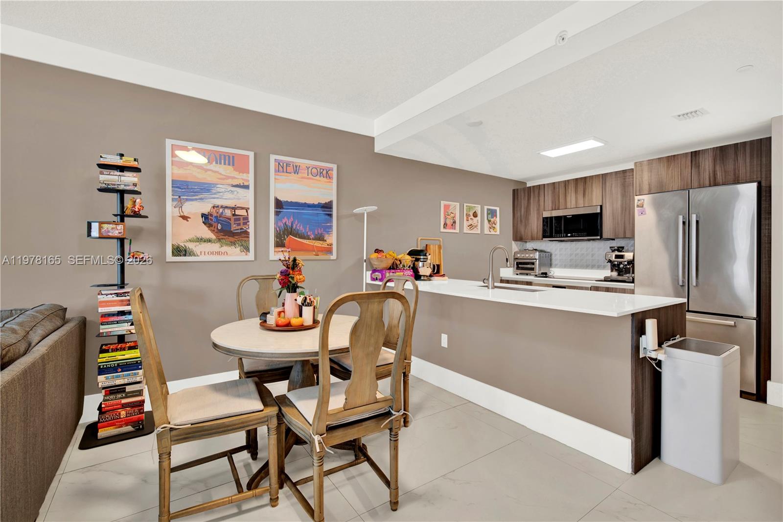 A dining area with a round table and wooden chairs sits beside an open kitchen — 488 NE 18th St # 2507, Miami FL 33132, MIAMI, FL