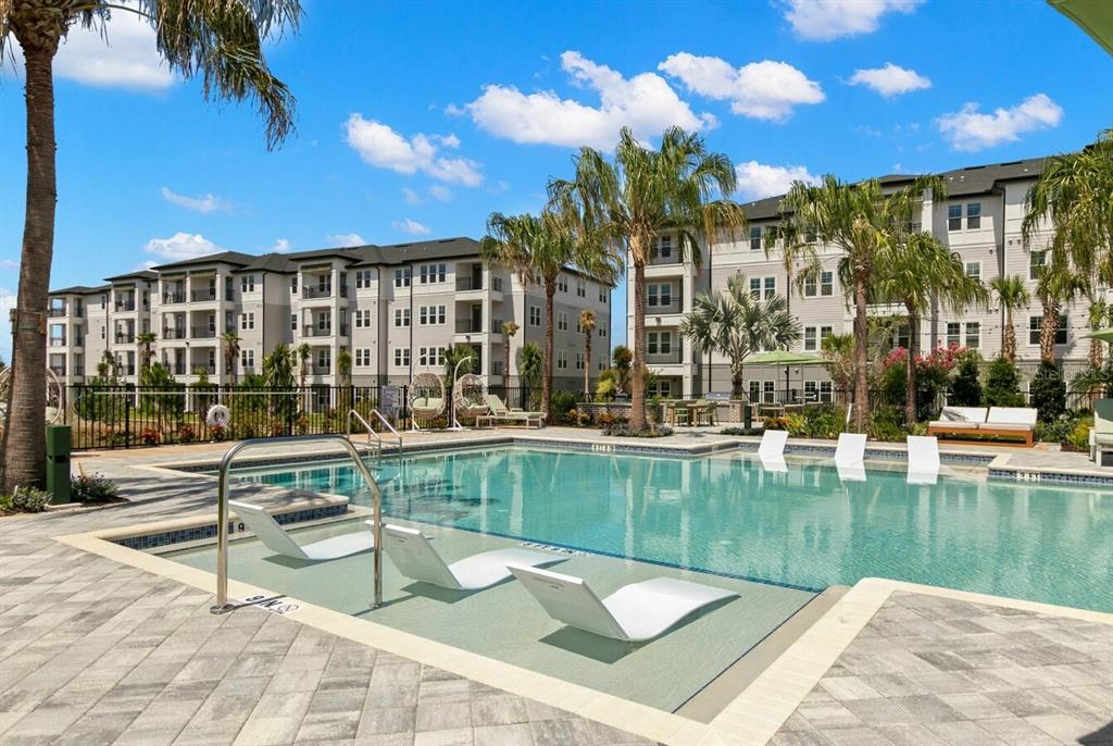 A swimming pool with lounge chairs sits in front of multi-story apartment buildings — 1310 RIDGEVIEW CIRCLE UNIT C1, DAVENPORT, FL