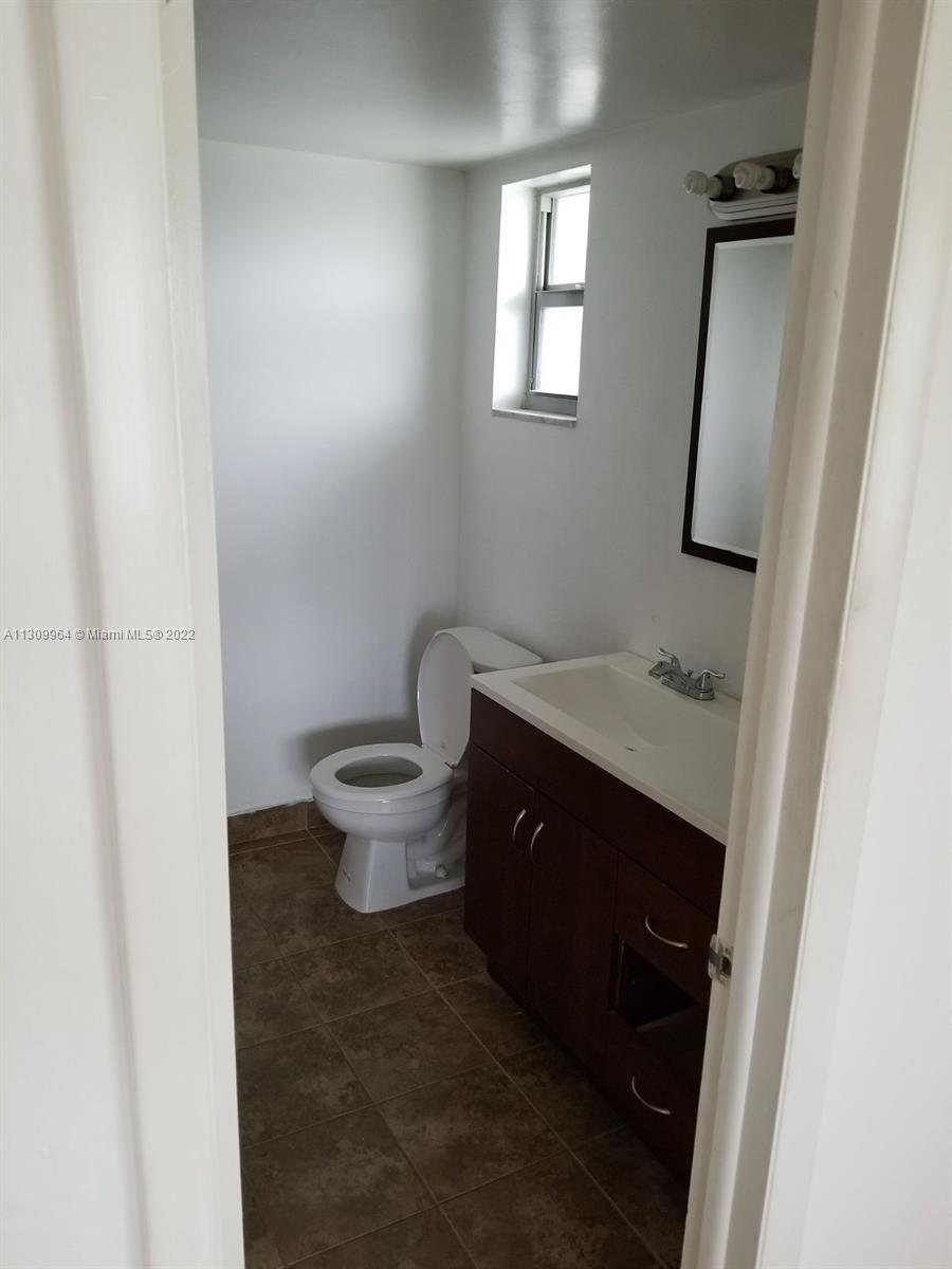 A small bathroom features a white toilet, a dark wood vanity, and a rectangular mirror — 5790 Stirling Rd # 314, Hollywood FL 33021, HOLLYWOOD, FL
