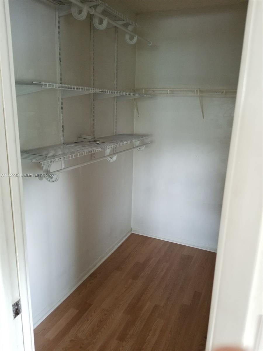 A walk-in closet features white wire shelving, a hanging rod, and light wood-look flooring — 5790 Stirling Rd # 314, Hollywood FL 33021, HOLLYWOOD, FL