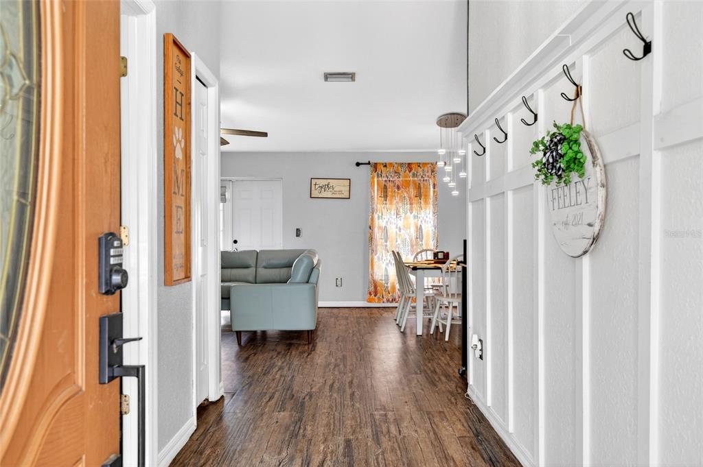 A view from an entryway into a living and dining area with wood-look flooring — 45 LARCH RADIAL, OCALA, FL