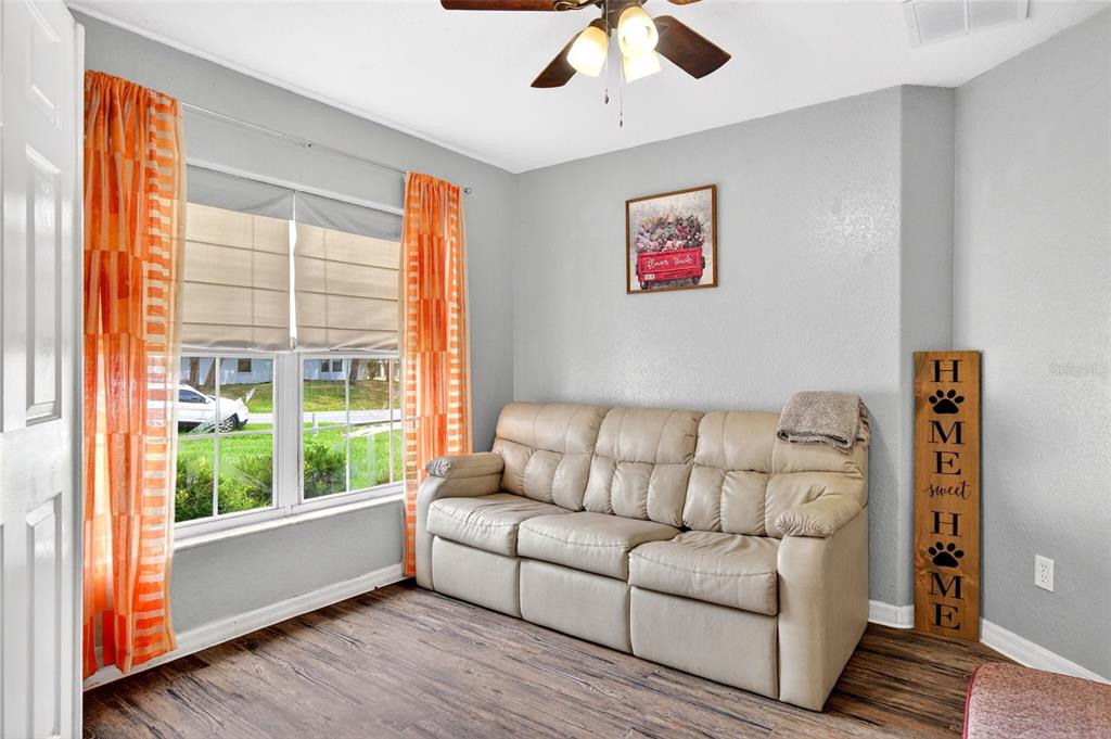 A living room features a beige reclining sofa, orange patterned curtains, and wood-look flooring — 45 LARCH RADIAL, OCALA, FL