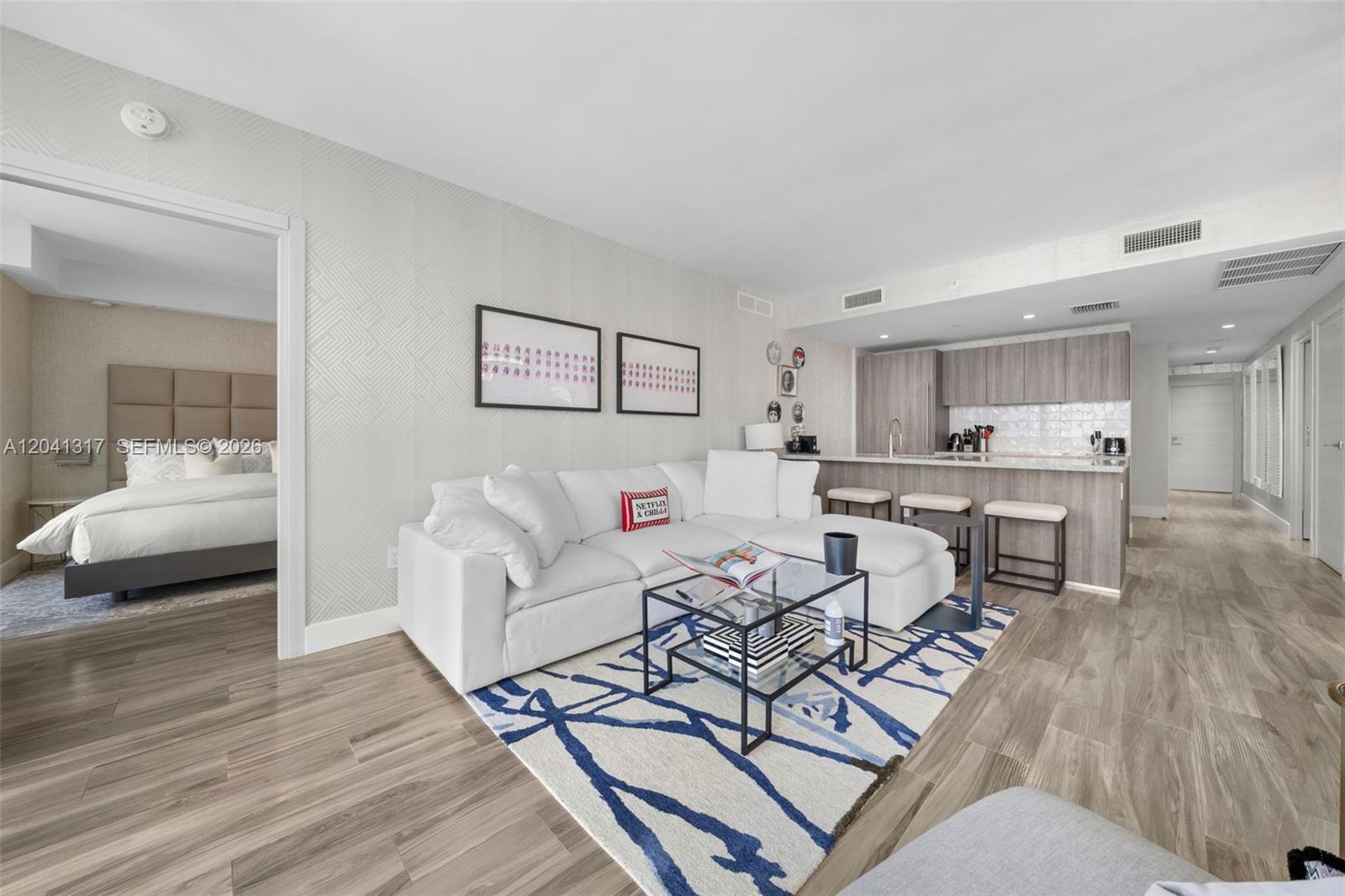 A modern living room with a white sectional sofa, glass coffee table, and open kitchen — 801 S Miami Ave # 1604, Miami FL 33130, MIAMI, FL