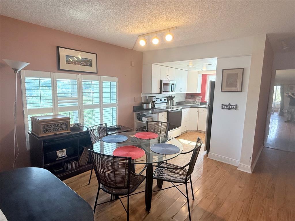 A dining area with a glass table and chairs sits adjacent to a white kitchen — 1200 37TH STREET N UNIT 409, ST PETERSBURG, FL