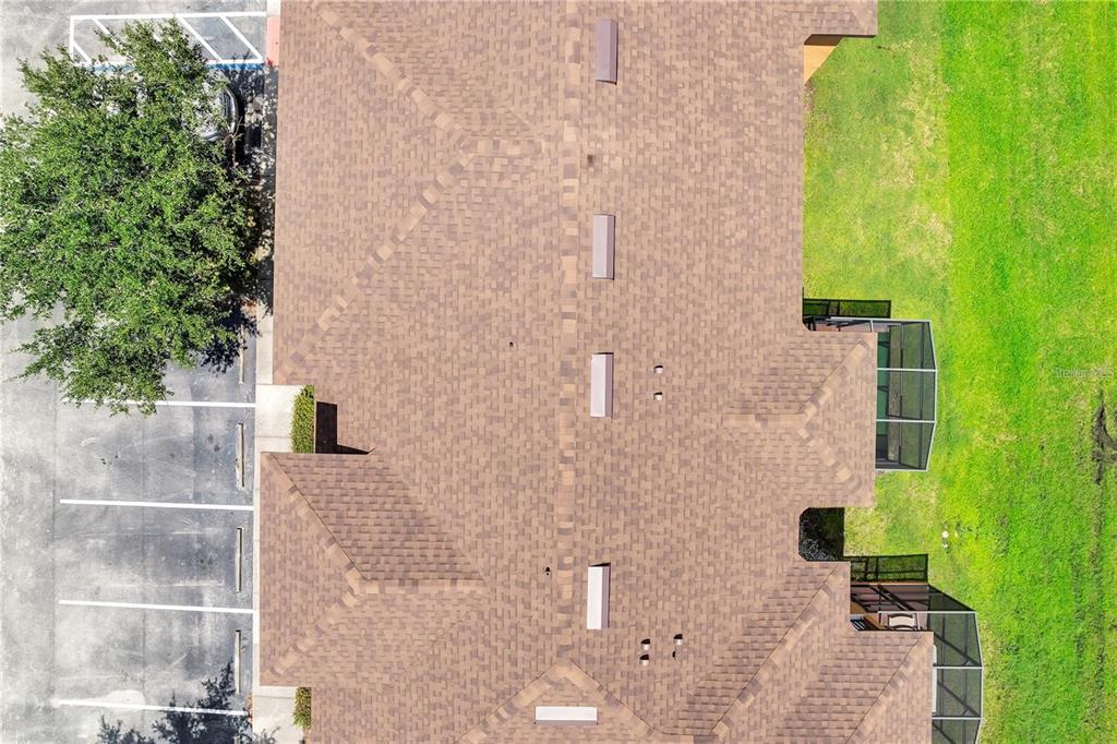 An aerial view shows the shingled roof of a building with skylights and screened lanais — 2713 BUSHMAN DRIVE, KISSIMMEE, FL