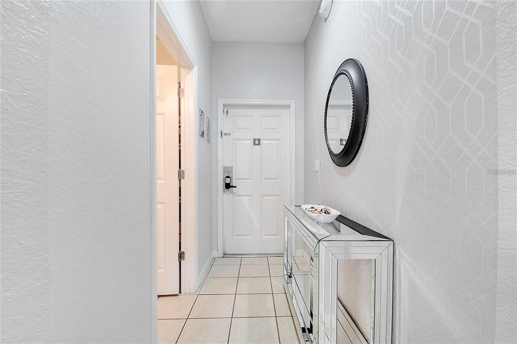 A tiled entryway features a mirrored console table, a round black mirror, and white walls — 2713 BUSHMAN DRIVE, KISSIMMEE, FL