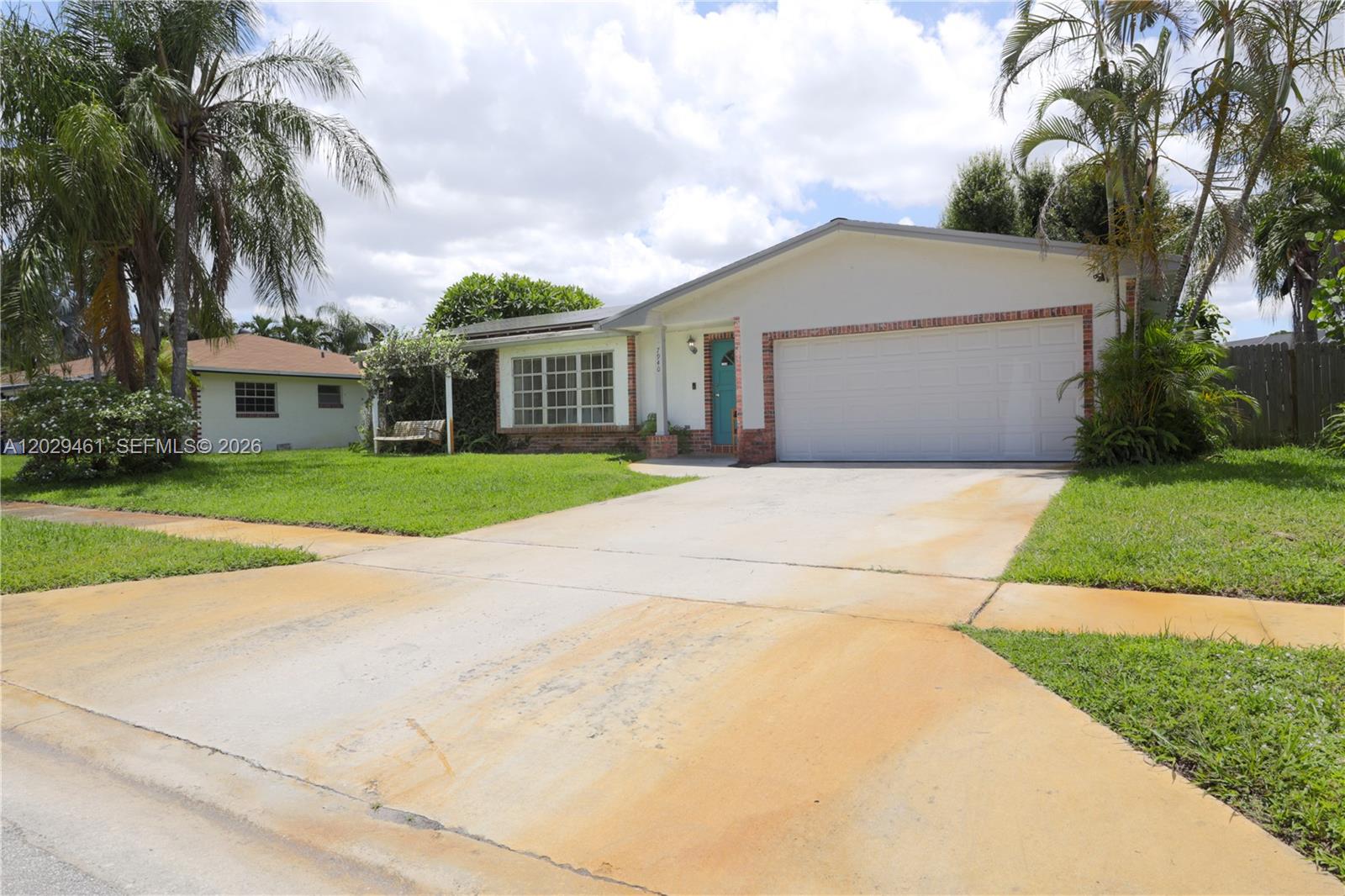 A single-story house features a white exterior, a two-car garage, and a teal front door — 7940 NW 9th St, Margate FL 33063, MARGATE, FL