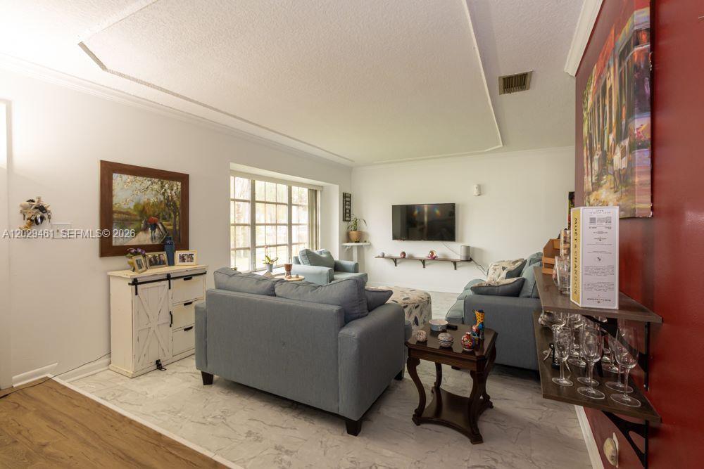 A living room features light-colored tile floors, two blue sofas, and a wall-mounted television — 7940 NW 9th St, Margate FL 33063, MARGATE, FL