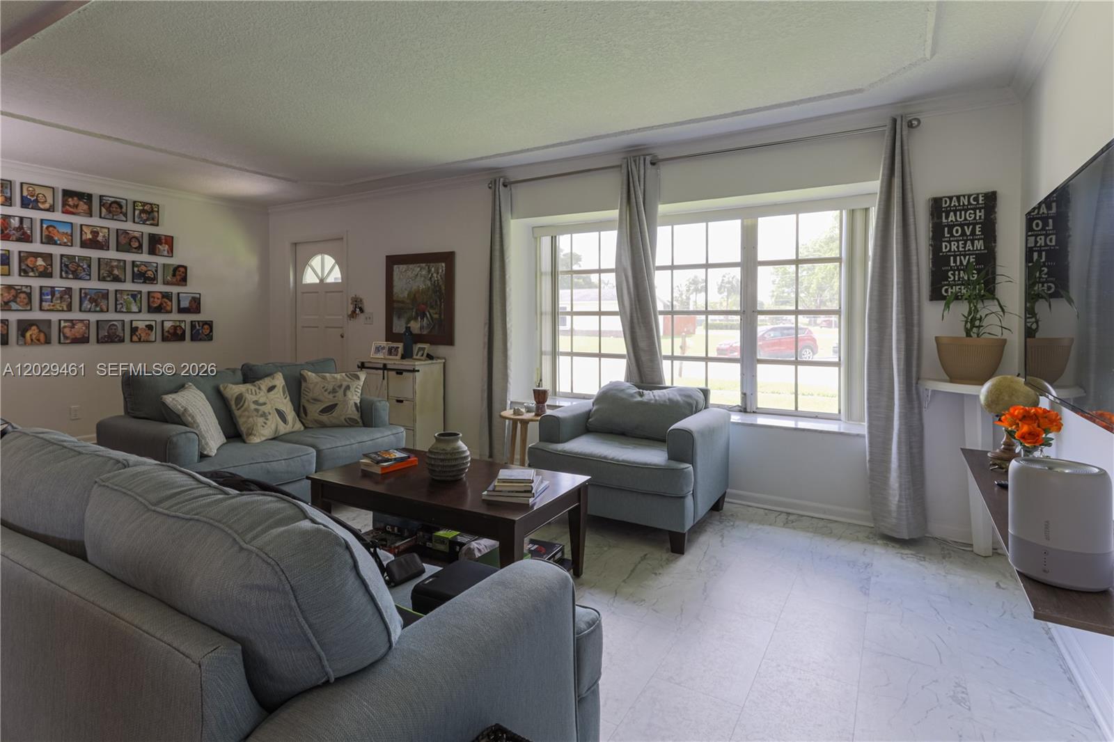 A living room features light blue furniture, a dark wood coffee table, and a photo gallery wall — 7940 NW 9th St, Margate FL 33063, MARGATE, FL