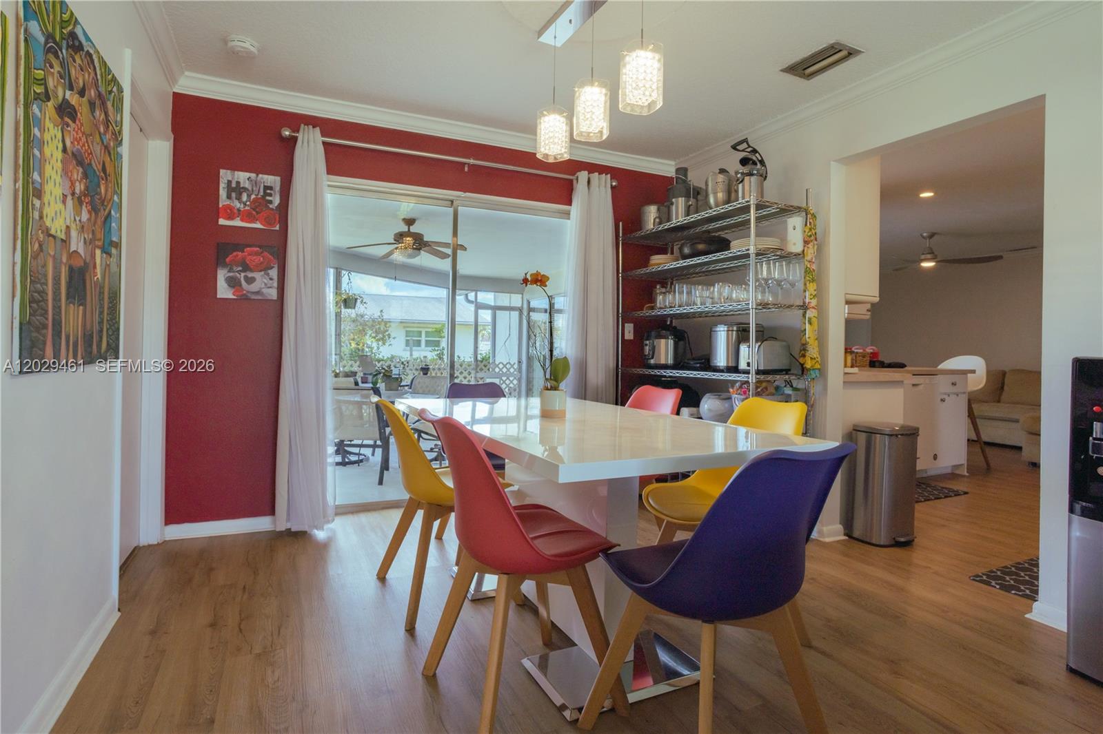 A dining room features a white table, colorful chairs, a red accent wall, and metal shelving — 7940 NW 9th St, Margate FL 33063, MARGATE, FL