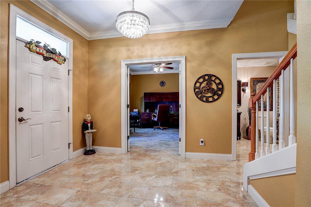 An entryway with tile flooring, a crystal chandelier, a staircase, and doorways to other rooms — 5518 LUMINAR POINTE LANE, APOLLO BEACH, FL