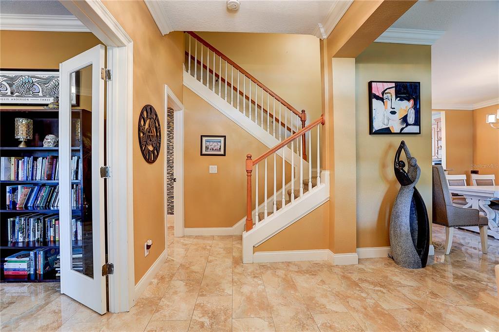 An entryway features a staircase with wooden railings, tile flooring, and a glass-paneled door — 5518 LUMINAR POINTE LANE, APOLLO BEACH, FL