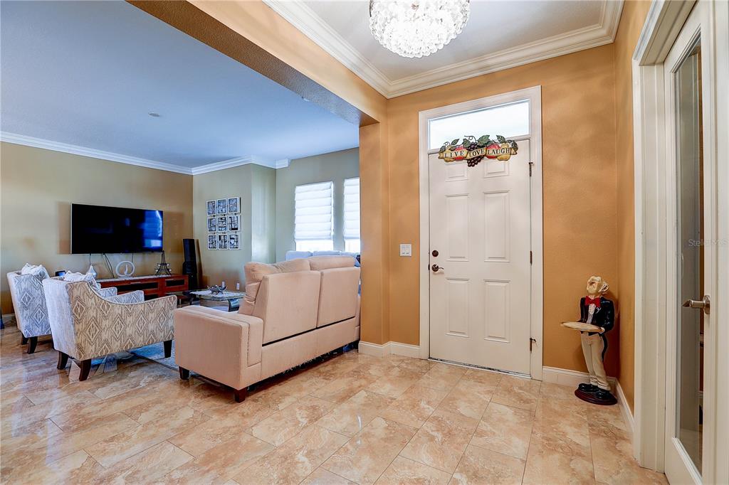 A tiled entryway leads into a living room with a sofa, armchairs, and a television — 5518 LUMINAR POINTE LANE, APOLLO BEACH, FL