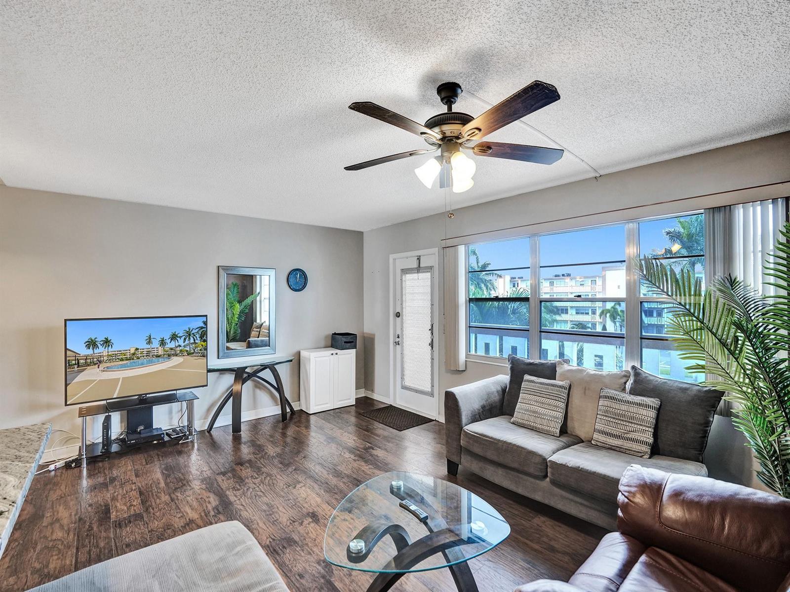 A living room features dark wood floors, a ceiling fan, a sofa, and a glass-topped table — 3014 Cornwall A, Boca Raton FL 33434, BOCA RATON, FL