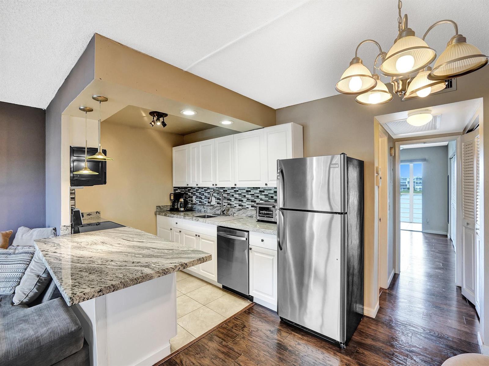 A kitchen features white cabinets, granite countertops, stainless steel appliances, and a breakfast bar — 3014 Cornwall A, Boca Raton FL 33434, BOCA RATON, FL