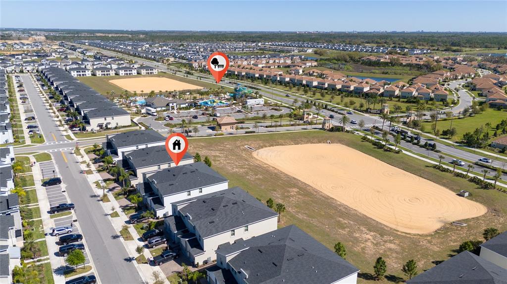 An aerial view shows a residential neighborhood with houses, a large sandy lot, and amenities — 1133 CHALLENGE DRIVE UNIT 1133, DAVENPORT, FL