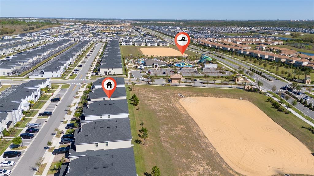 An aerial view shows townhomes, a large sandy lot, and a community pool complex — 1133 CHALLENGE DRIVE UNIT 1133, DAVENPORT, FL