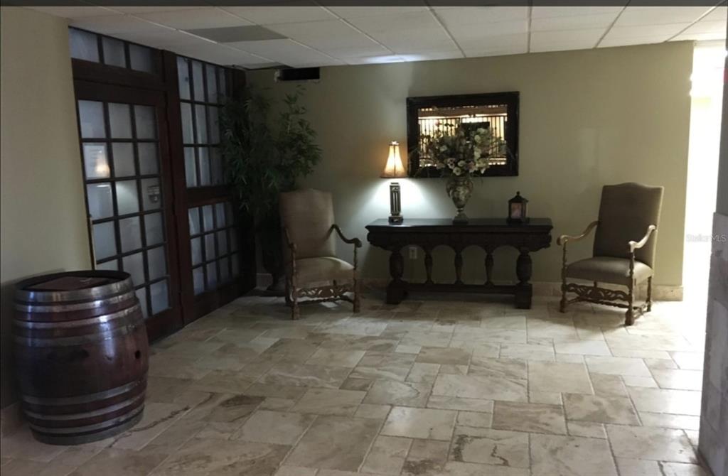 A lobby area features stone tile flooring, two armchairs, a console table, and a wooden barrel — 3501 S ATLANTIC AVENUE UNIT 3210, DAYTONA BEACH, FL