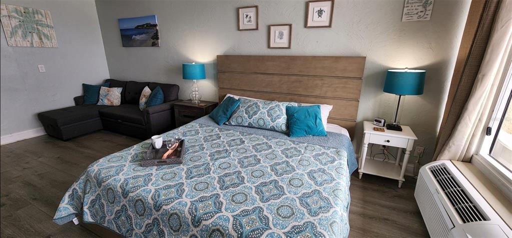 A bedroom features a bed with a patterned quilt, a sofa, and two bedside lamps — 3501 S ATLANTIC AVENUE UNIT 3210, DAYTONA BEACH, FL