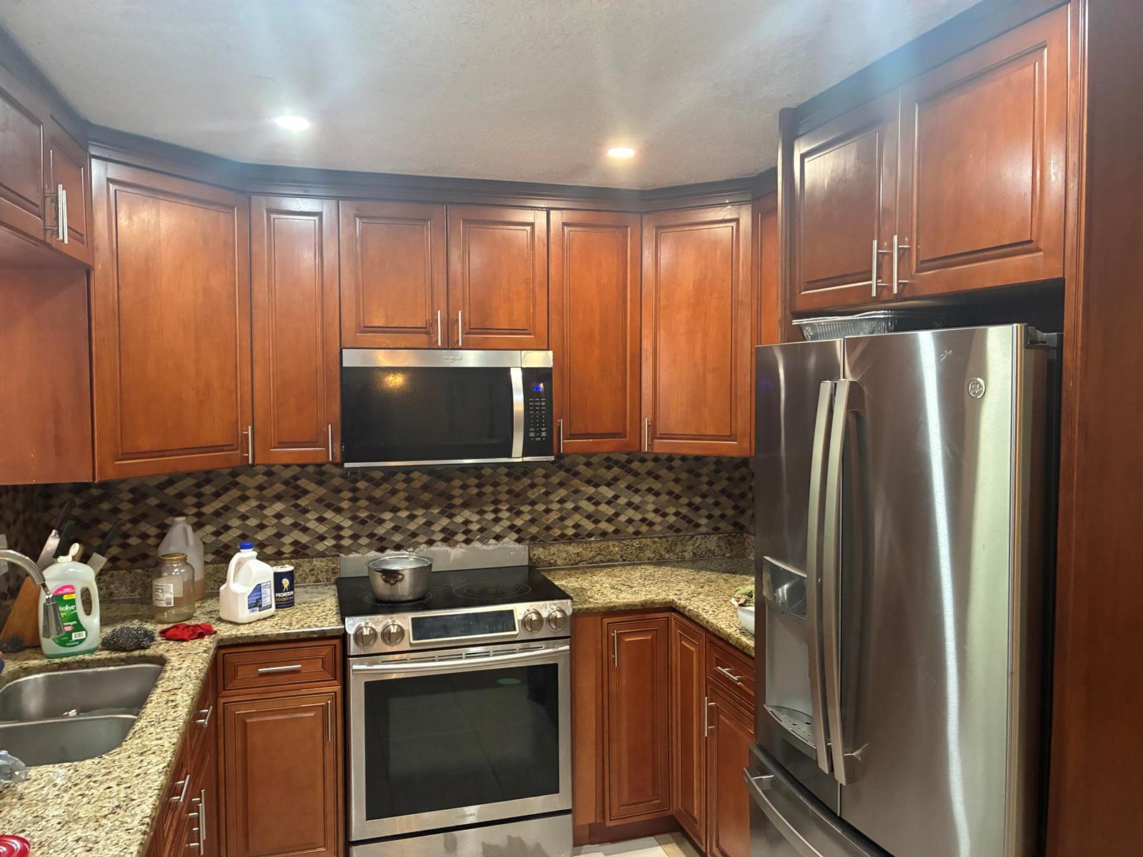 A kitchen features wood cabinets, stainless steel appliances, granite countertops, and a mosaic tile backsplash — 3120 NE 8th Avenue, Pompano Beach FL 33064, POMPANO BEACH, FL