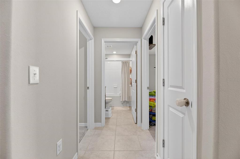 A tiled hallway leads from a coat rack toward a distant room with a window — 11216 KELLY GREEN AVENUE, WIMAUMA, FL