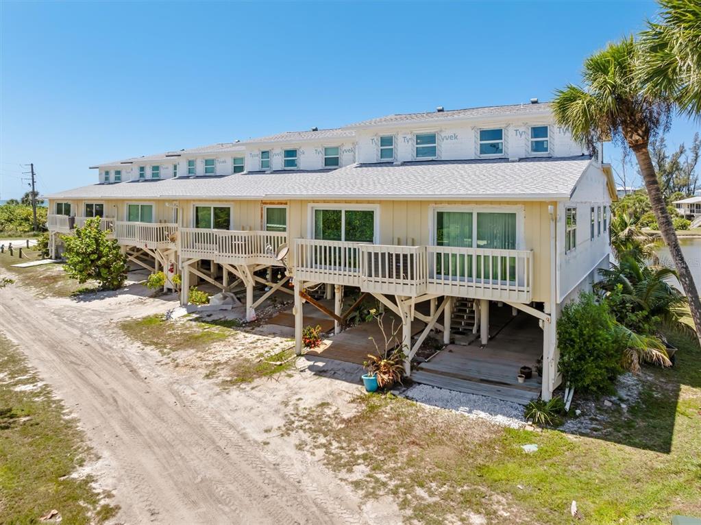 An elevated multi-unit residential building with light yellow siding and wooden decks — 9400 LITTLE GASPARILLA ISLAND UNIT G9, BOCA GRANDE, FL