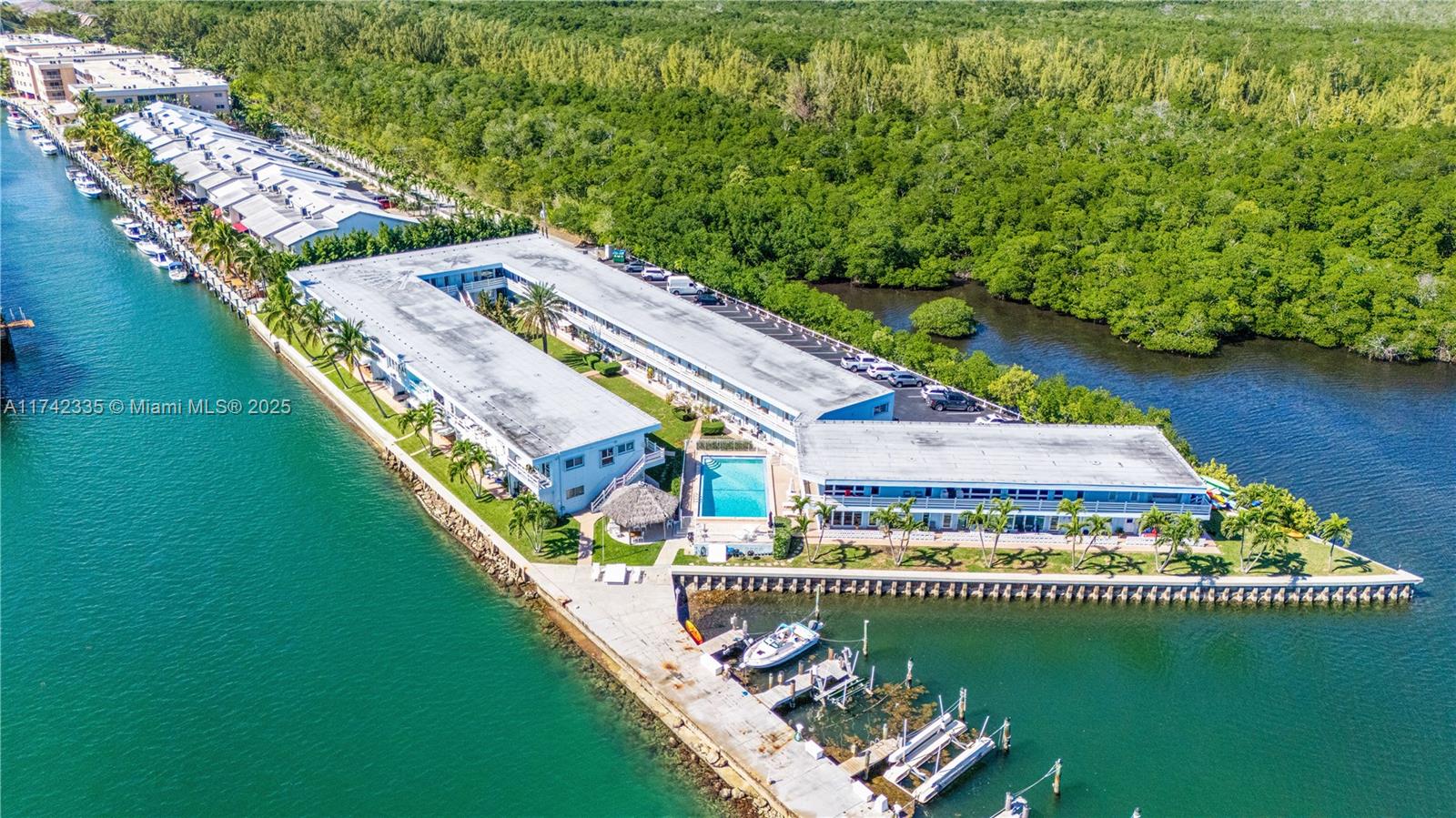 An aerial view shows a waterfront apartment complex with a pool, docks, and parking — 2700 NE 135th St # 32, North Miami FL 33181, NORTH MIAMI, FL
