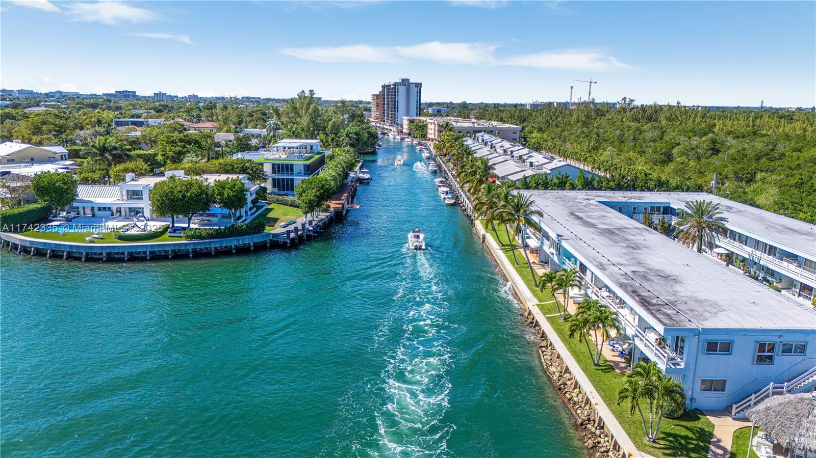 An aerial view shows a canal with a boat moving between waterfront residential buildings — 2700 NE 135th St # 32, North Miami FL 33181, NORTH MIAMI, FL