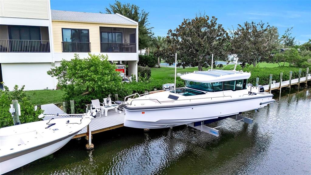 A white boat is docked on a lift next to a house on a canal — 4104 128TH STREET W UNIT 702, CORTEZ, FL