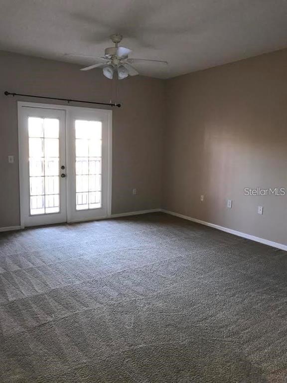 A carpeted room features a ceiling fan and a set of French doors — 10831 WINDSOR WALK DRIVE UNIT 1308, ORLANDO, FL