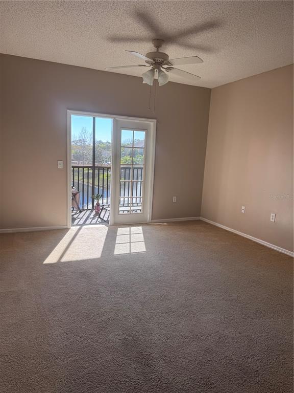A carpeted bedroom features a ceiling fan, beige walls, and a glass door to a balcony — 10831 WINDSOR WALK DRIVE UNIT 1308, ORLANDO, FL
