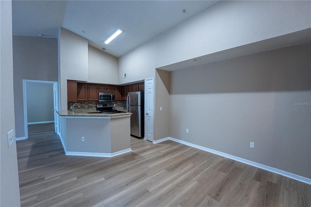 A kitchen with dark wood cabinets and stainless steel appliances opens to a living area — 13028 PLANTATION PARK CIRCLE UNIT 1225, ORLANDO, FL