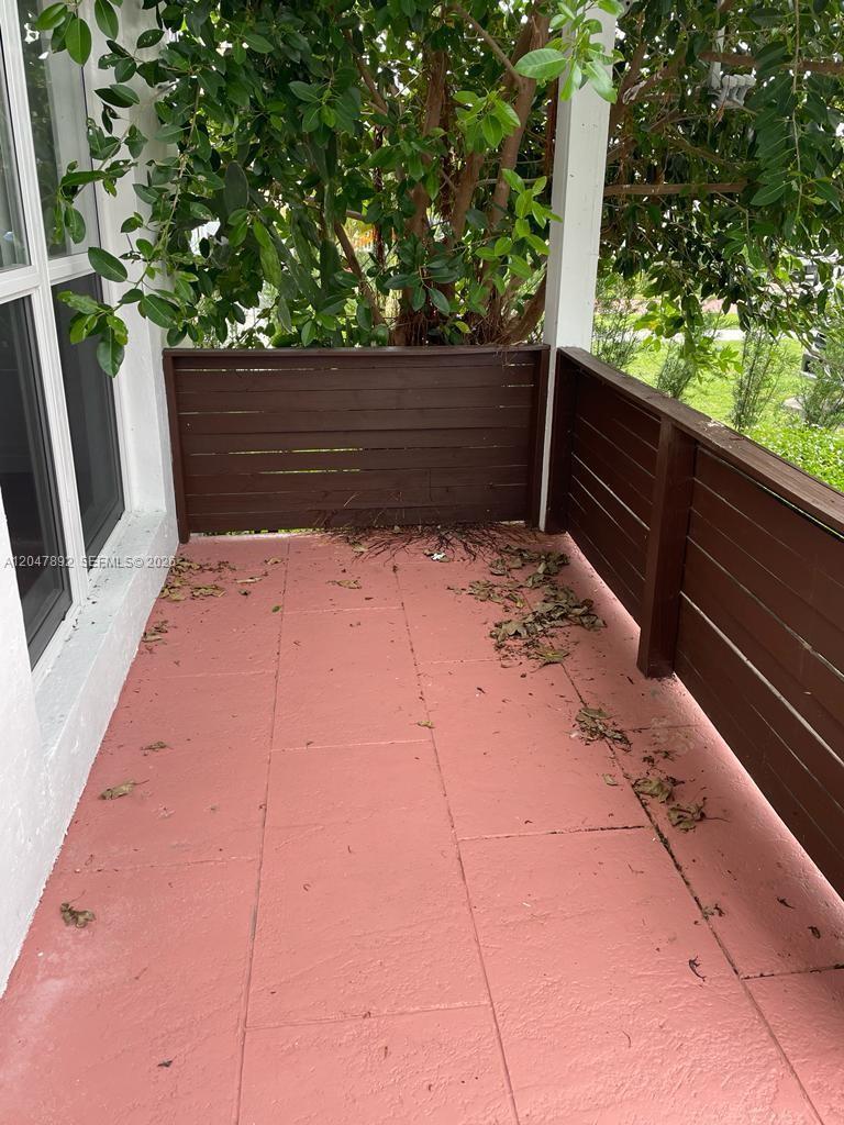A small outdoor balcony features red tiled flooring and dark brown wooden privacy railings — 757 85th St, Miami Beach FL 33141, MIAMI BEACH, FL