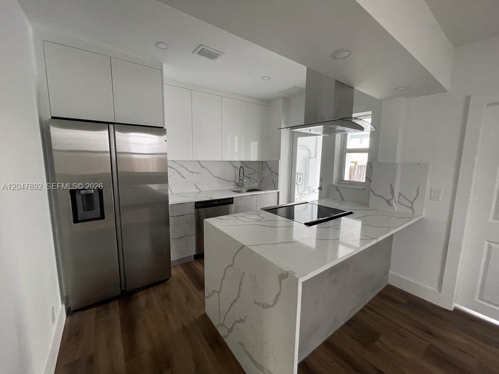 A modern kitchen features white cabinetry, marble-patterned countertops, stainless steel appliances, and wood-look flooring — 757 85th St, Miami Beach FL 33141, MIAMI BEACH, FL