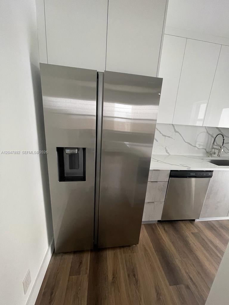 A stainless steel refrigerator stands next to white cabinets and a marble-patterned backsplash — 757 85th St, Miami Beach FL 33141, MIAMI BEACH, FL