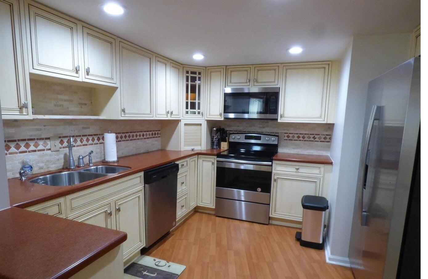A kitchen with cream cabinets, red countertops, stainless steel appliances, and light wood flooring — 2800 N Ocean Drive # 5c, Singer Island FL 33404, SINGER ISLAND, FL