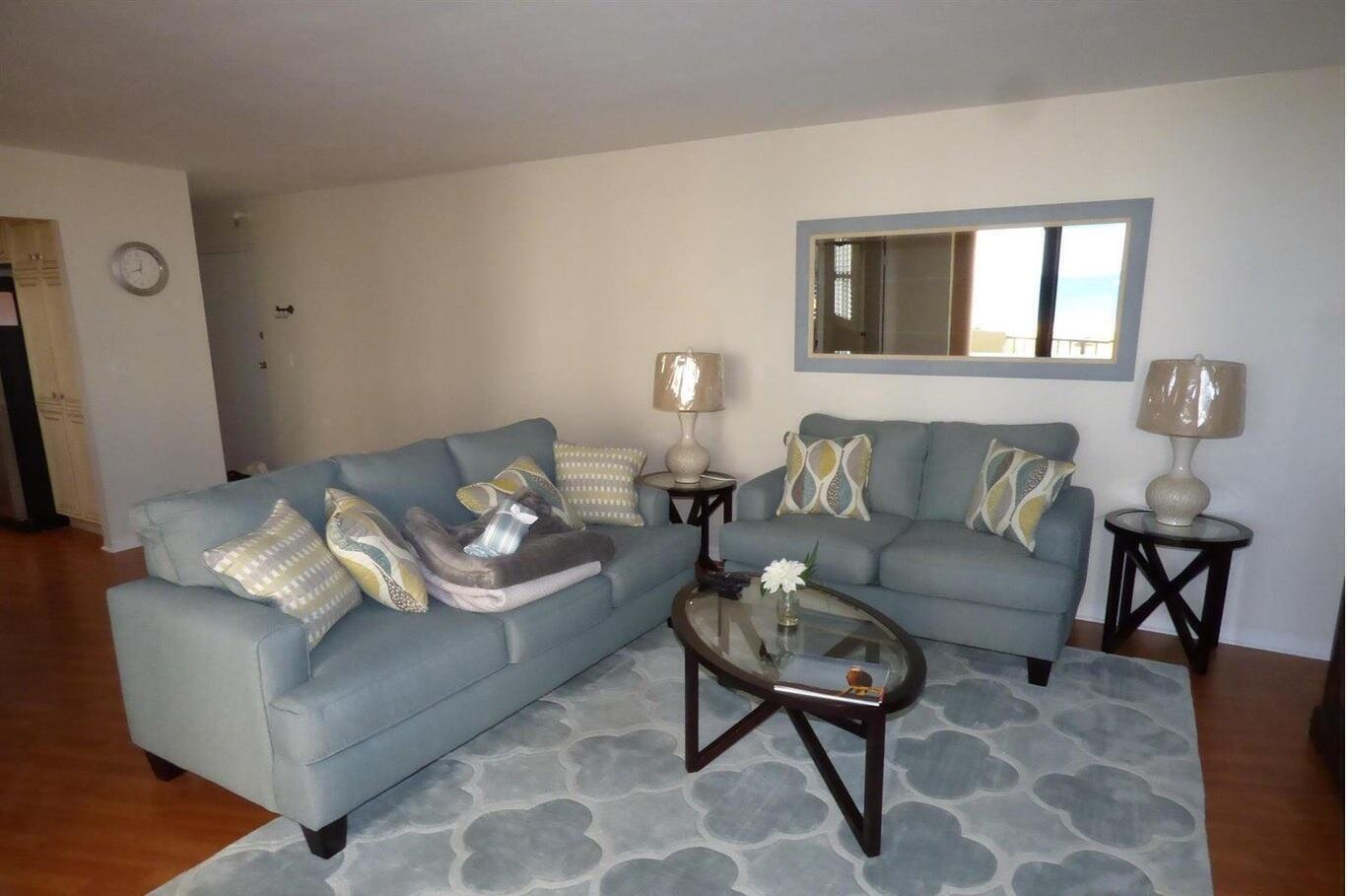 A living room features two light blue sofas, a glass coffee table, and a patterned rug — 2800 N Ocean Drive # 5c, Singer Island FL 33404, SINGER ISLAND, FL