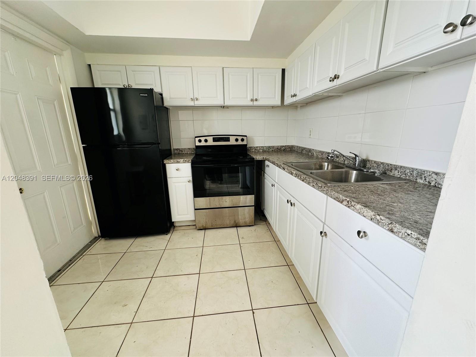 A kitchen features white cabinets, granite countertops, a black refrigerator, and a stainless steel stove — 6740 Arbor Dr # 204, Miramar FL 33023, MIRAMAR, FL