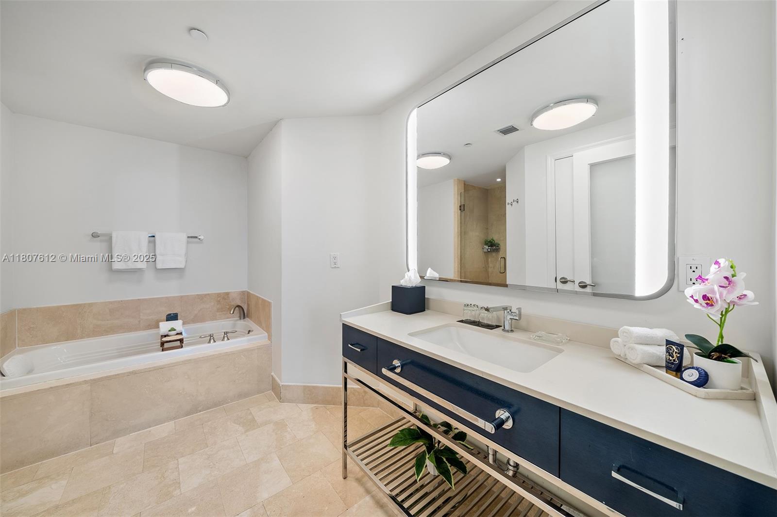 A bathroom features a soaking tub, a blue vanity with a white countertop, and mirror — 4401 Collins Ave # 3505, Miami Beach FL 33140, MIAMI BEACH, FL