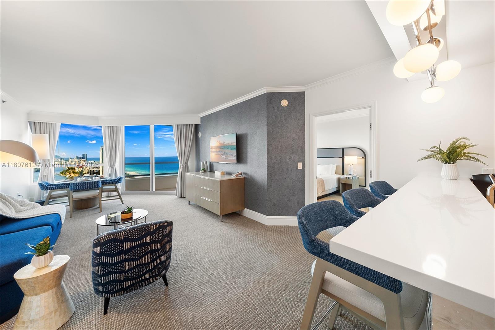 A living room and dining area feature blue furniture, a gray accent wall, and ocean views — 4401 Collins Ave # 3505, Miami Beach FL 33140, MIAMI BEACH, FL
