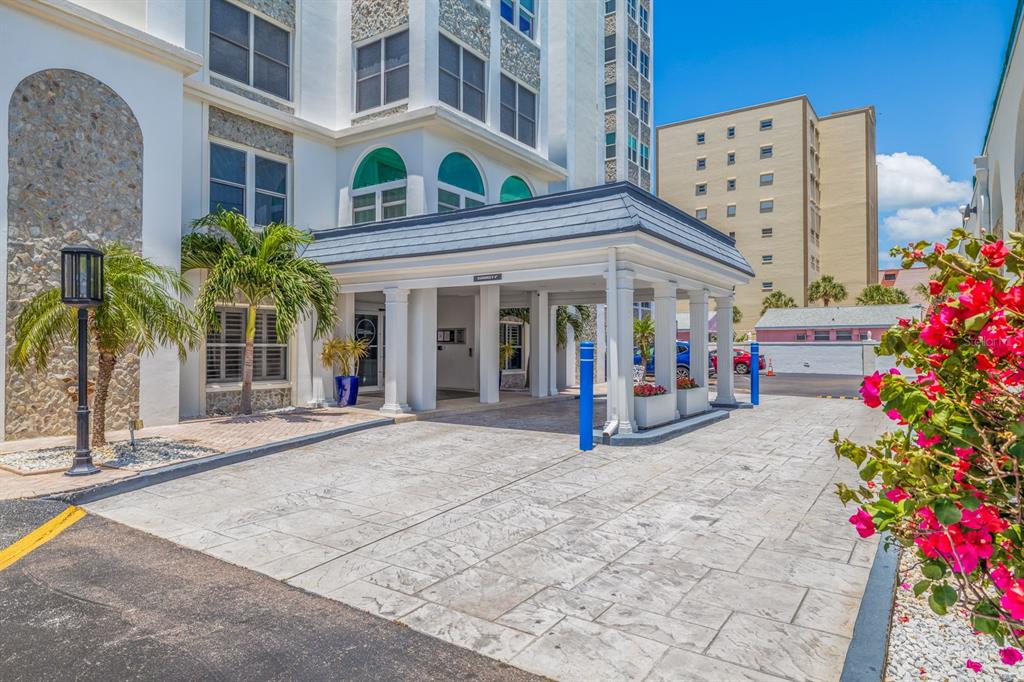 A paved driveway leads to the covered entrance of a multi-story building with stone accents — 4950 GULF BOULEVARD UNIT 404, ST PETE BEACH, FL