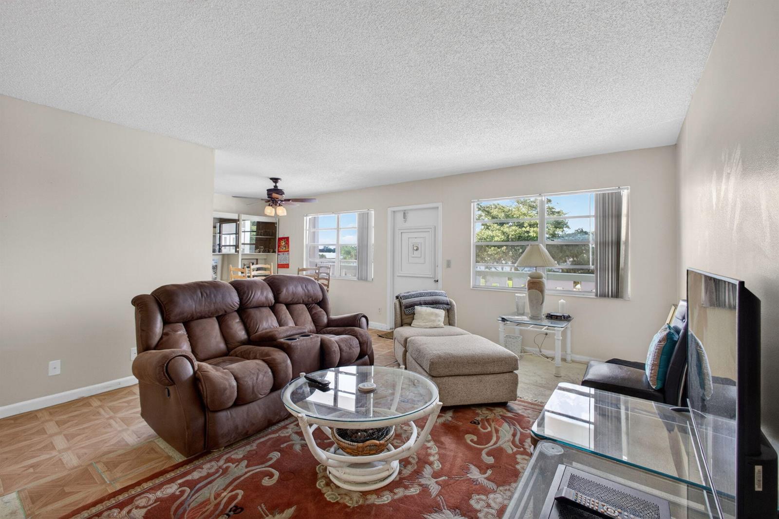 A living room features a brown reclining sofa, a glass coffee table, and a chaise lounge — 348 Wellington H, West Palm Beach FL 33417, WEST PALM BEACH, FL